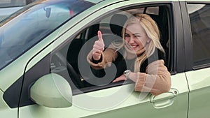 Happy smiling girl in the car showing thumb up.