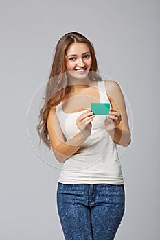 Happy smiling girl in casual clothing, showing blank credit card