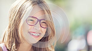 Happy smiling girl with dental braces and glasses. Young cute ca