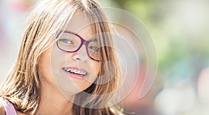 Happy smiling girl with dental braces and glasses. Young cute ca