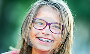 Happy smiling girl with dental braces and glasses. Young cute caucasian blond girl wearing teeth braces and glasses