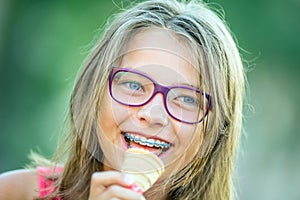 Happy smiling girl with dental braces and glasses. Young cute caucasian blond girl wearing teeth braces and glasses