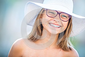 Happy smiling girl with dental braces and glasses. Young cute caucasian blond girl wearing teeth braces and glasses