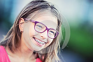 Happy smiling girl with dental braces and glasses. Young cute caucasian blond girl wearing teeth braces and glasses