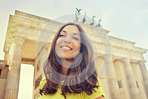 Happy smiling girl in front of Brandenburg Gate, Berlin, Germany. Beautiful young woman travel in Europe.