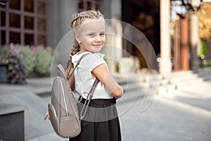 Happy smiling girl is going to school for the first time with bag go to elementary school. Pupil go study with backpack