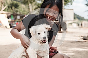 Happy smiling girl holding a white dog puppy in her hand outdoor