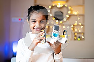 Happy Smiling Girl kid with small DIY robot in Hand looking at camera - Concept of Child Prodigy, Scientific experiment, Knowledge