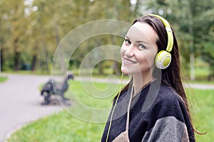 Young happy woman listening music from smartphone with headphones in a quiet Park