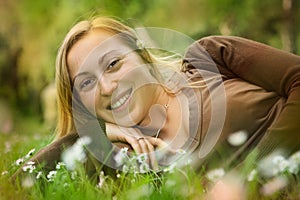 Happy smiling girl lying in grass on a meadow