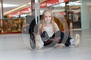 Happy and smiling girl with mini segway at trading mall. Teenager riding on hover board or gyroscooter.