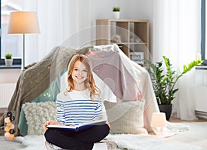 Happy smiling girl reading book at home