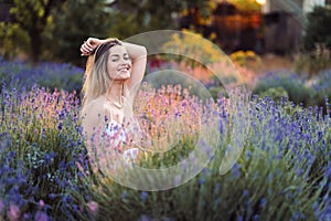 Happy Smiling Girl Sits Satisfied In The Lavender Field Throwing Her Hand Behind Her Head