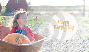 Happy smiling girl sitting inside wheelbarrow at field pumpkin patch