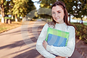 Happy smiling Girl teenager 12-15 years old, autumn day, street portrait, knitted white sweater, summer park. In hand