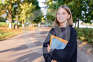 Happy smiling Girl teenager 12-15 years old, autumn day, street portrait, summer park. In hand notebooks folders