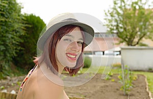 Happy smiling girl wearing straw hat in the garden