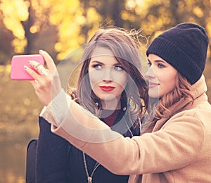 Happy Smiling Girls with Cell Phone Taking Selfie in Autumn Park