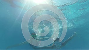 Happy smiling girls dive in swimming pool, underwater shoot, having fun