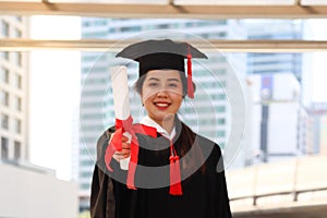 Happy smiling graduated student, young beautiful Asian woman warming square academic hat cap and giving certificate to camera,