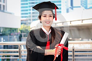 Happy smiling graduated student, young beautiful Asian woman wearing square academic hat cap, holding certificate, standing with