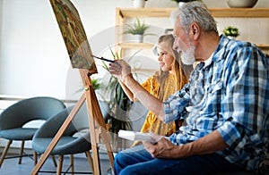 Happy smiling grandfather and grandchild painting together. Family, generation, happiness concept