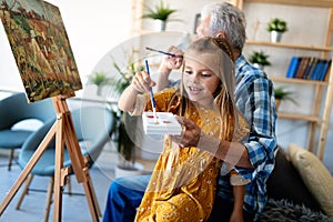 Happy smiling grandfather and grandchild painting together. Family, generation, happiness concept