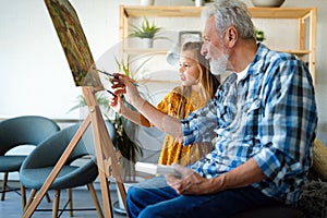 Happy smiling grandfather and grandchild painting together. Family, generation, happiness concept