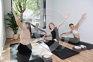 Happy smiling group practicing yoga in front of an instructor, doing side bends