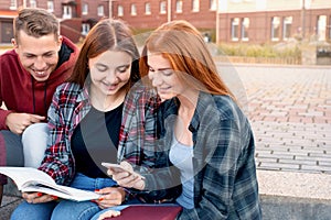 Happy smiling group of students studying outdoors near university