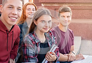 Happy smiling group of students studying outdoors near university