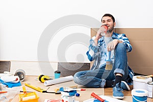 Happy smiling guy relaxing on floor with coffee