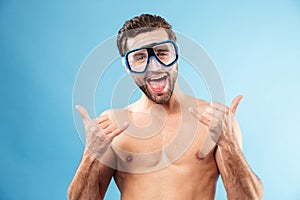 Happy smiling guy in swimming goggles showing thumbs up gesture