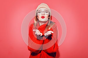 Happy Smiling Hipster Girl kiss in knitted red sweater and hat having fun . Cute girl in glusses with piercing in the nose.