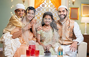 Happy smiling indian muslim couple with kids in traditional dress by looking at camera during ramdan fest celebration