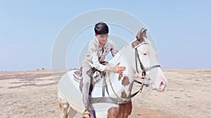 happy smiling Joyful man riding a white horse on a sandy terrain desert raising arms in excitement under a clear sky