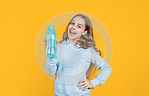 happy smiling kid girl hold water bottle for drinking after sport workout, thirsty