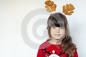 Happy smiling kid in a red knitted pullover with a Santa hat on head isolated on white background.