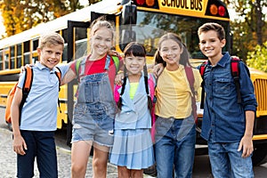 Happy smiling kids waiting next to yellow school bus