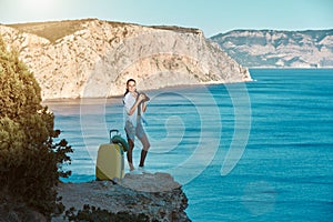 Happy smiling lady standing on sea view. Yellow luggage for journey. New ground and business travel concept, copy space