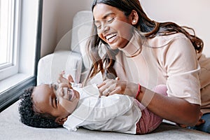 Happy smiling laughing Indian mother playing with black baby girl daughter. Family mixed race people mom and a kid together