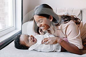 Happy smiling laughing Indian mother playing with black baby girl daughter. Family mixed race people mom and a kid together