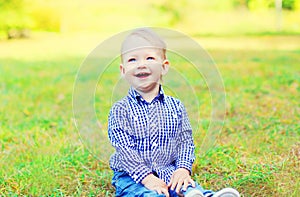 Happy smiling little boy child sitting on grass