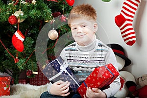 Happy smiling little boy with christmas gift boxes