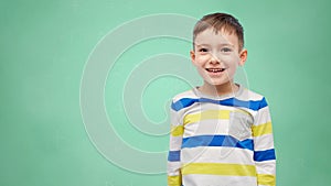 Happy smiling little boy over green school board