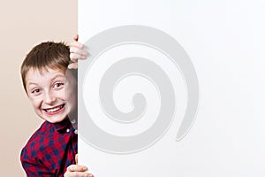 Happy smiling little boy, showing white blank placard, board,poster.Facial expression.