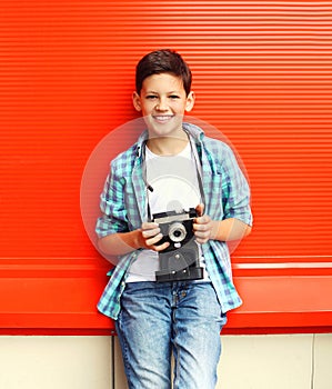 Happy smiling little boy teenager with retro vintage camera