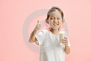 Happy Smiling Little Brunette Child Girl Drinking Milk From Glass With a Trace Frm Milk on Lips, Expresses Pleasure