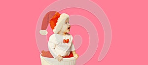 Happy smiling little child in christmas santa red hat playing with toys looking away on blank copy space for advertising text on