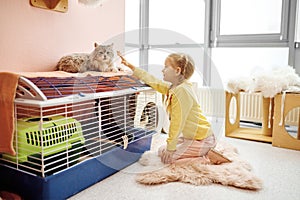Happy smiling little girl child playing with cat indoors